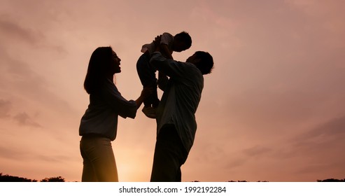 silhouette of asian parent play with kid and dad hug the boy outdoor