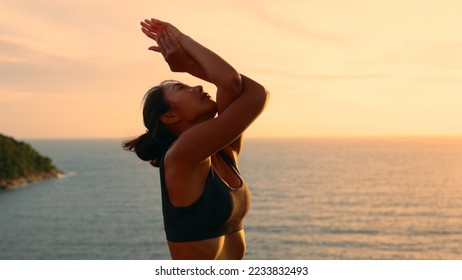 Silhouette of Asian woman improves balance for body, mind and spirit with yoga practice at sunset on the beach. Slow movements and deep breathing improves strength and flexibility. mental health - Shutterstock ID 2233832493