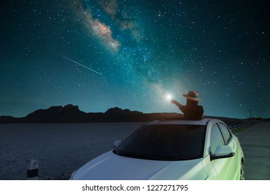 Silhouette Asian Women Standing Alone In A Sunroof At The Lake Scenic Spot. Watching The Sky And The Milky Way At Night. Long Exposure, With Grain.