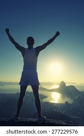 Silhouette des Athleten in weißer SportUniform mit Champion-Arme erhöht vor Rio de Janeiro Brasilien Sonnenaufgang Skyline Blick auf den Zuckerhut