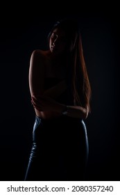 Silhouette Of Attractive And Young Girl Is Posing In Studio While Being Dressed In All Black Clothes