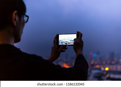 silhouette of Back view young man takes pictures by cellphone on the rooftop bar in the cityscape with bokeh background - Powered by Shutterstock