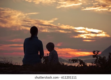 Silhouette Back View Young Mother And Child Enjoying The View, Mist, Mountains, Sunset. Mountain Peaks In The Fog Islands. Friendly Family. North Norway, Lofoten Islands, Ocean, Fjords, Scandinavia