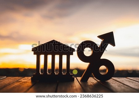 Silhouette of Bank symbol and Percentage model on wood table. Concepts of the banking system, rising interest rates, inflation, deflation, and savings.	