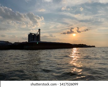 Silhouette Of Barges And Grain Silo On Tennessee River In Decatur, AL At Sunset