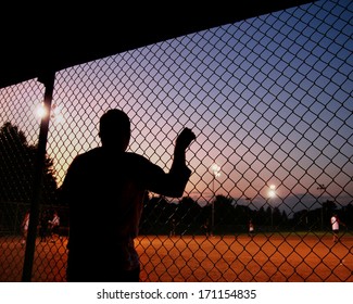 a silhouette of a baseball/softball player in the dugout