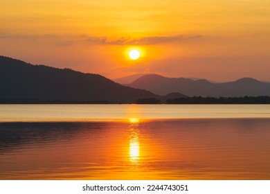 Silhouette, beautiful landscape with sunset at coast of the lake in summer. Nature landscape. reflection, orange sky and yellow sunlight, romantic. Amazing scene at lake in Huai Mai Teng, Thailand