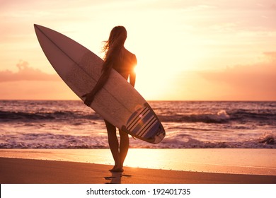 Silhouette Of Beautiful Surfer Girl On The Beach At Sunset