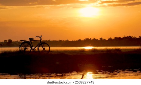 Silhouette bicycle sunset golden sky background. Bike park in nature garden outdoors country leisure lake view on sunrise water reflection sunbeam at dawn. Silhouette bicycle biking golden landscape - Powered by Shutterstock