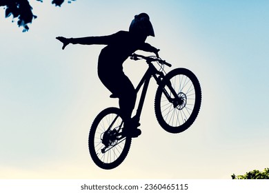 Silhouette of a biker performing an extreme dirty jump with a bmx bike against the sky  - Powered by Shutterstock