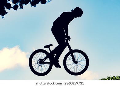 Silhouette of a biker performing an extreme dirty jump with a bmx bike against the sky - Powered by Shutterstock