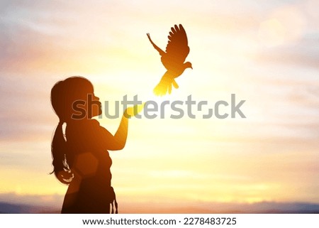 silhouette of bird flying out of Girl child hand on beautiful background.freedom concept ,International Working Women's Day