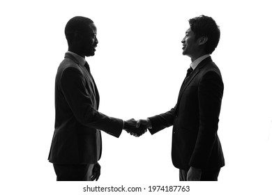 Silhouette of black and asian people shaking hands. Global business. - Powered by Shutterstock