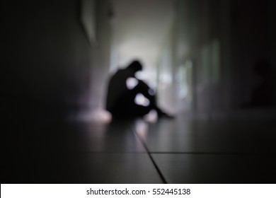 Silhouette of blurred adult man in walkway of condominium or office, low key tone and dark with sad mood as for background. Sad man or stressed human is very depressred and upset.
