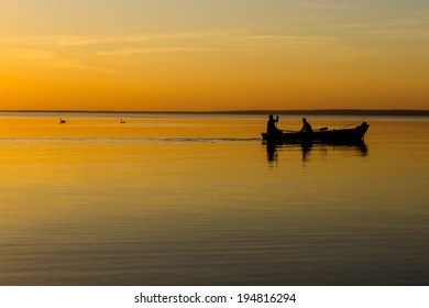 Silhouette of boats and fishermen on a lake at sunset