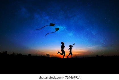 Silhouette Of Boy And Girl Flying A Kite In Milky Way Background.