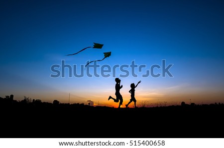 Silhouette of boy and girl flying a kite in sunset background.