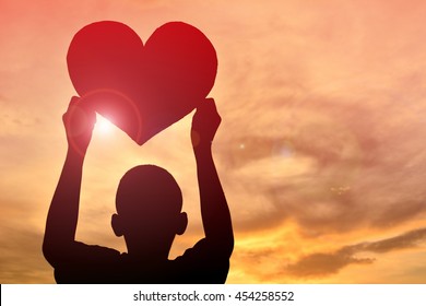 Silhouette Boy Holding Heart Shape At Sunset