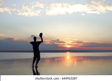 Silhouette of a boy playing american football or rugby at the beach with beautiful sunset background Childhood, serenity, sport, lifestyle concept. - Powered by Shutterstock