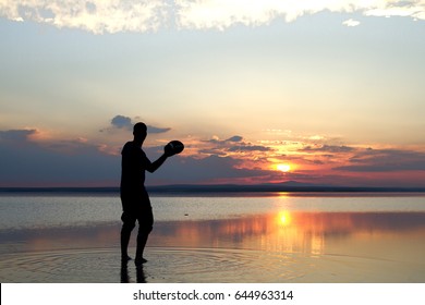 Silhouette of a boy playing american football or rugby at the beach with beautiful sunset background Childhood, serenity, sport, lifestyle concept. - Powered by Shutterstock