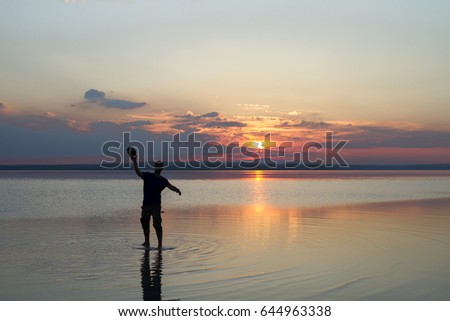 Silhouette of a boy playing american football or rugby at the beach with beautiful sunset background Childhood, serenity, sport, lifestyle concept.