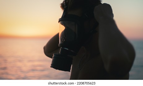 Silhouette Of A Boy Putting On His Gas Mask At Dawn In The Ocean