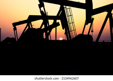 Silhouette Of - BPU Crude Oil Pumps Beans Close Up  In  The Oilfield At Sunset - Selective Focus