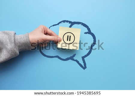 The silhouette of the brain and the pause icon on the sticker. A symbol of the need to rest the brain