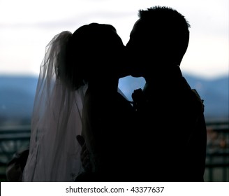 Silhouette Of A Bride And Groom Kissing At The Alter