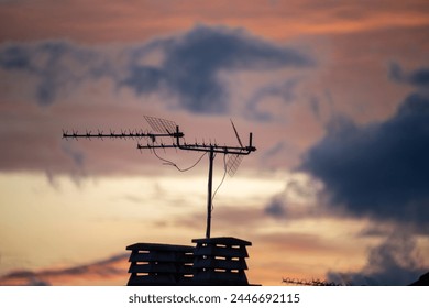 Silhouette of a building, on the roof there are two chimneys and a TV antenna during dusk. - Powered by Shutterstock