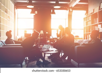 Silhouette Of Business Group Discussing New Plan. Team Meeting On The Couch. Big Open Space Office. Five People. Intentional Sun Glare