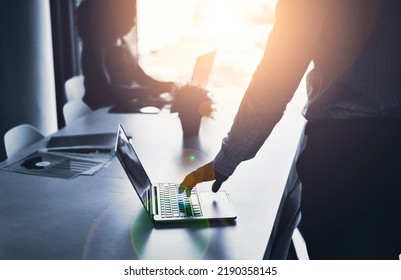 Silhouette Of A Business Man Hand Working On A Laptop At An IT Company And Having A Meeting In An Office. A Male Employee Typing In A Dark Boardroom During A Meeting Or Presentation