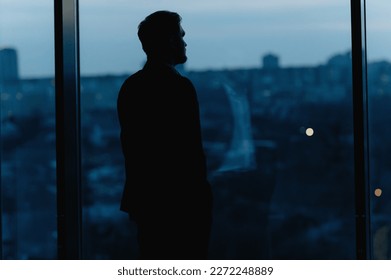 Silhouette of a Business Man looking out of high rise office window at night - Shutterstock ID 2272248889