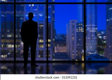 Silhouette of a Business Man looking out of high rise office window at night - Powered by Shutterstock