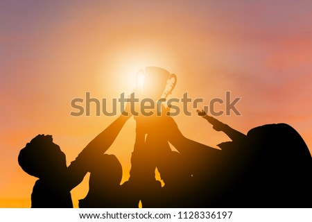 Silhouette of Business team with clipping path holding award trophy show their victory when business success sunset background