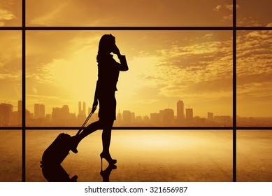 Silhouette of business woman walking with suitcase over city background. Business travel concept