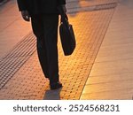 Silhouette of a businesses man walking through the city carrying a bag or a briefcase 