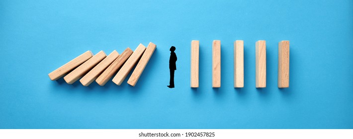 Silhouette of a businessman in apathy or inertia against collapsing wooden dominos on blue background. Business crisis and inactivity concept.