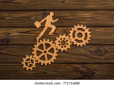 silhouette of a businessman with a briefcase going to success through gear set. Career growth, promotion, and teamwork. Of natural wood background. - Powered by Shutterstock