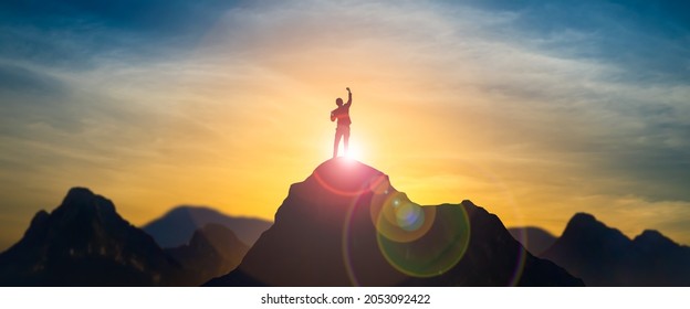 Silhouette of businessman celebrating raising arms on the top of mountain with over blue sky and sunlight.concept of leadership successful achievement with goal,growth,up,win and objective target. - Shutterstock ID 2053092422