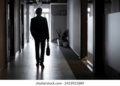 Silhouette of a businessman in full height, a man inside the office walks along the corridor, companies, an employee in a business suit. - Powered by Shutterstock