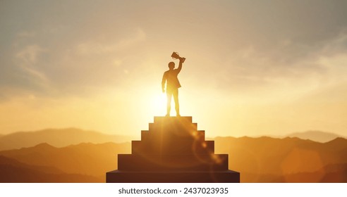 Silhouette of businessman holding a trophy on top staircase with light sunset. concept of a successful business or determination to lead the organization to success. - Powered by Shutterstock