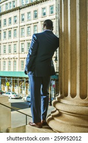 Silhouette Of Businessman On The Phone. Facing Street, Lowering His Head, A Young Black Guy Standing By Column Outside Office, Talking On His Mobile Phone. Back View. Instagram Filtered Look. 