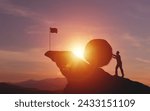 Silhouette of businessman pushing a large rock up hill with flag showing finish line on sunset scene. concept of determination and effort in solving problems, heavy workload