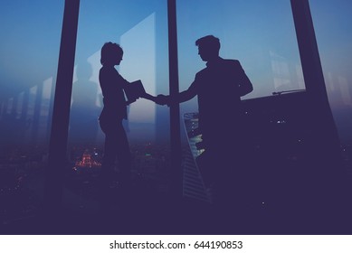 Silhouette of businessman shaking hands in honor of the transaction with his new woman partner, male and female entrepreneurs congratulate each other with their successful work - Shutterstock ID 644190853
