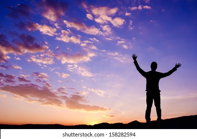 Silhouette of businessman standing on top mountain open arms looking at the sunrise or sunset - Shutterstock ID 158282594