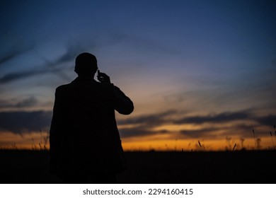 Silhouette of a businessman at sunrise in nature. The concept of business, negotiations, development, success, startups, new opportunities. - Powered by Shutterstock