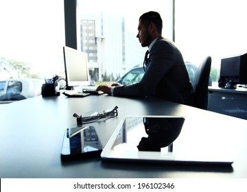 Silhouette of businessman using laptop in office  - Shutterstock ID 196102346