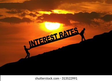 Silhouette of businessmen carrying Interest Rates word uphill