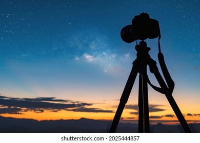 Silhouette of a camera on the tripod at the starry night and bright milky way galaxy.night landscape - Powered by Shutterstock